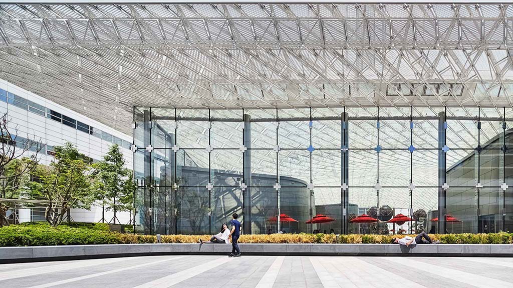 A person walking in front of a large glass building.