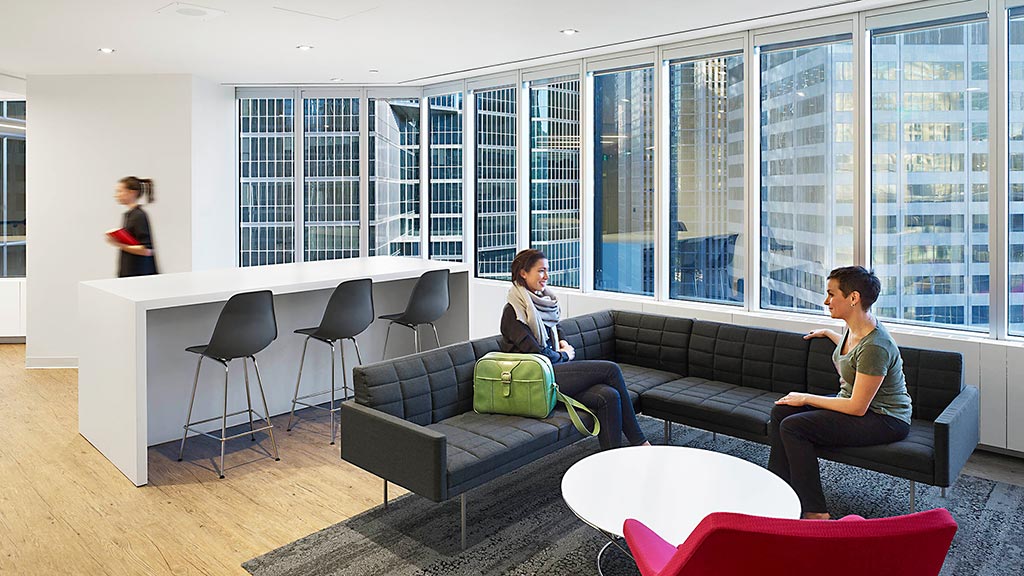 A group of people sitting on a couch in a room with a large window.