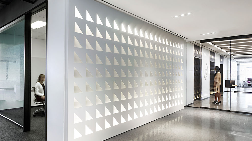 A person sitting in a chair in a room with a large white wall.