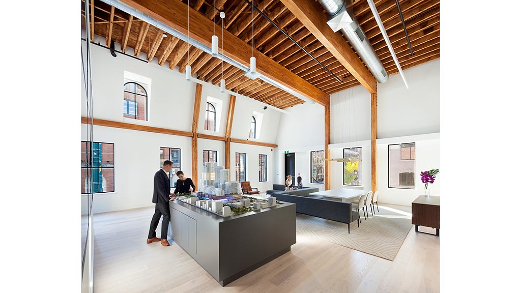 A person standing in a room with a large desk and a large ceiling.