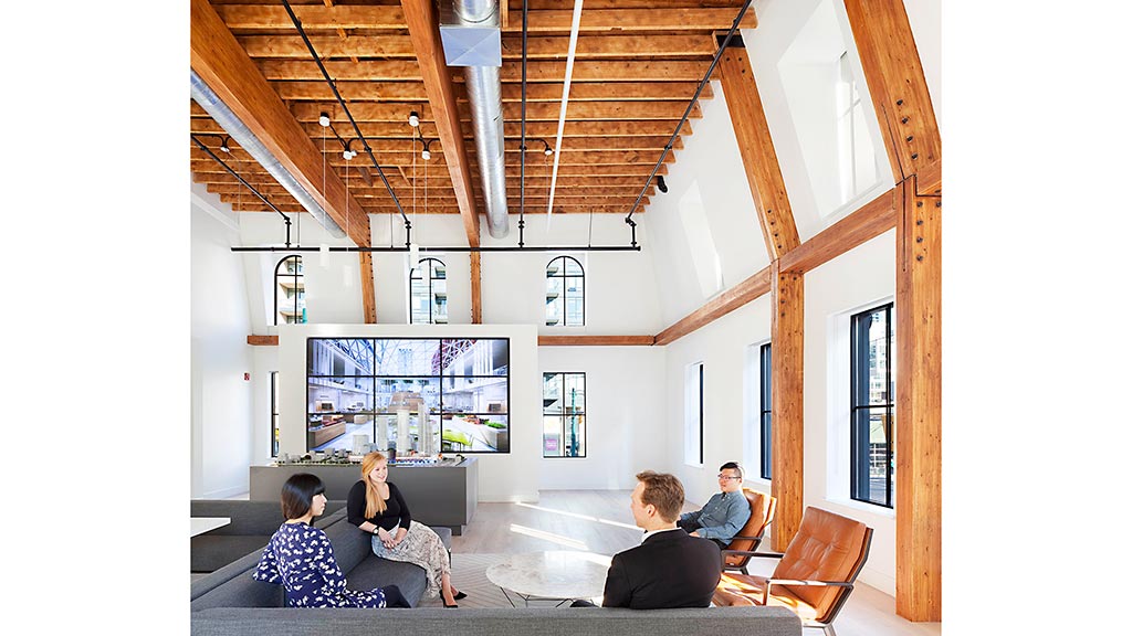 A group of people sitting in a room with a large screen.