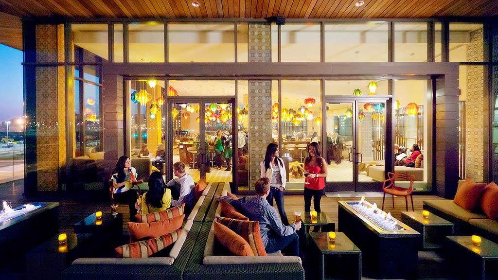 A group of people in a room with windows and a large glass wall.