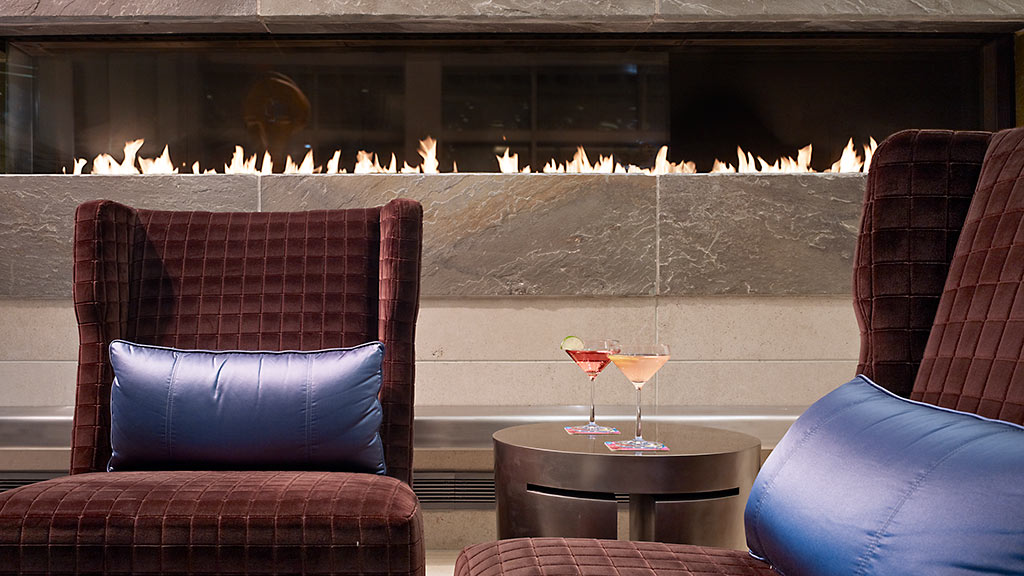 A room with couches and a table with a glass of wine.