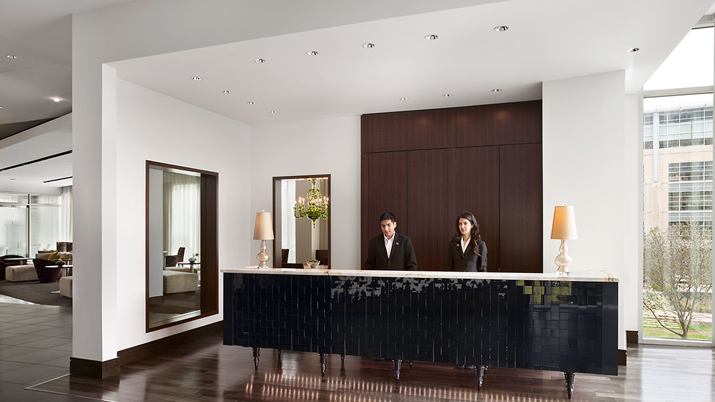 A man and woman standing behind a counter in a room with a large mirror.