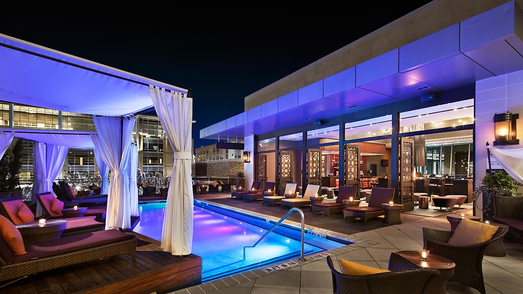 A pool with a lounge chair and a large window with a view of the ocean.