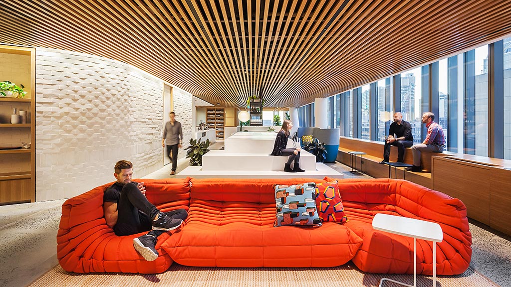 A group of people sitting on a couch in a room with windows.