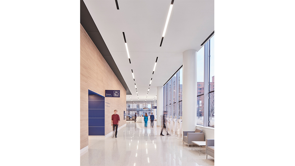 A long hallway with people and white pillars.