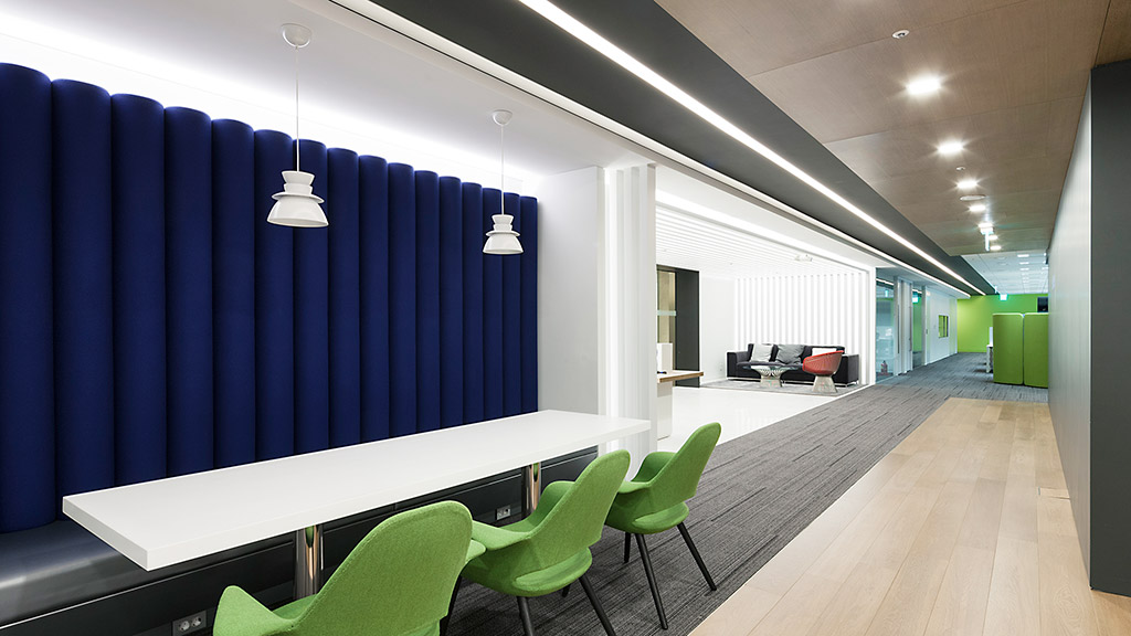A room with a blue wall and green chairs.