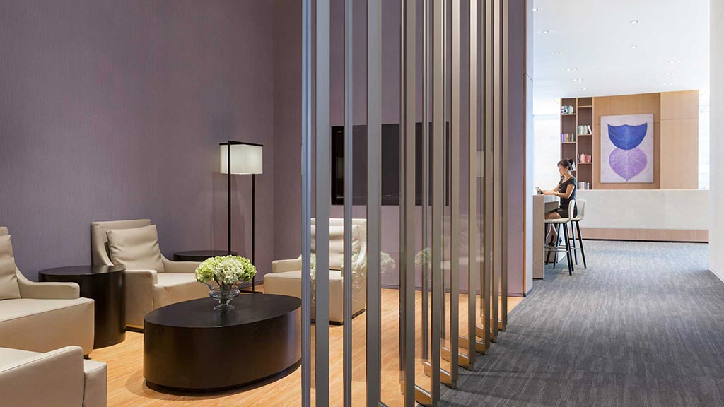 A person sitting at a desk in a room with a large glass door.