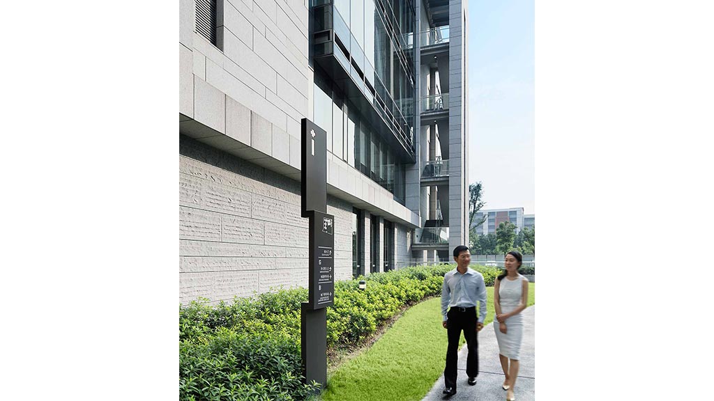 A man and woman walking down a sidewalk next to a building.