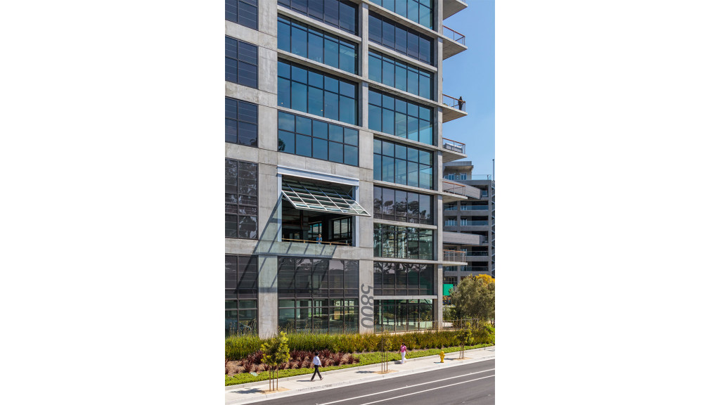 A building with a street and people walking on the sidewalk.