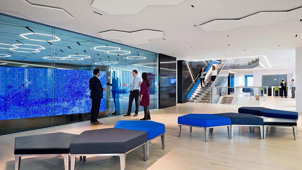 A group of people in a room with blue benches.