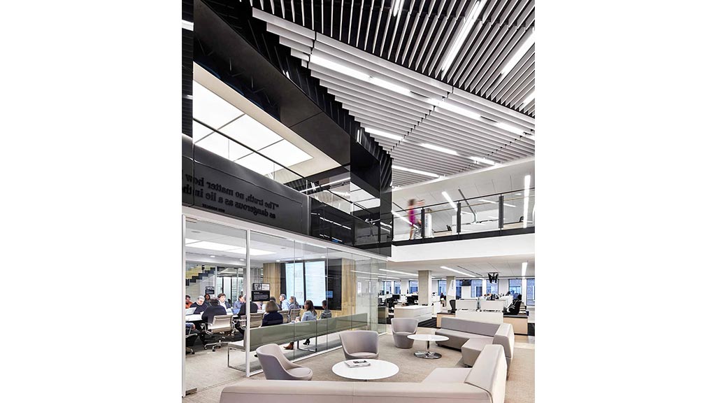 A group of people sitting in a room with white chairs and a large ceiling.