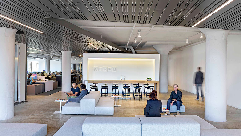 A group of people sitting in a room with white pillars.