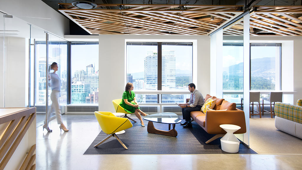 A group of people in a room with windows and a couch.
