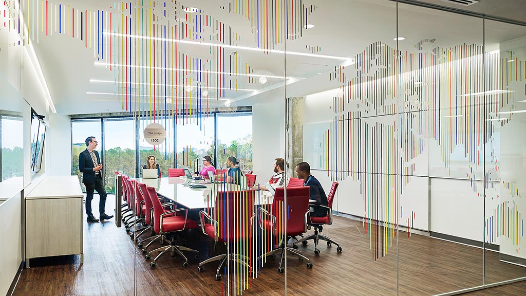 A group of people sitting at a table in a room with a large glass wall.
