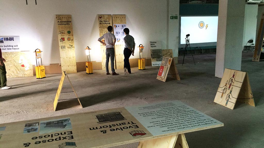 A group of people standing in a room with signs and posters.
