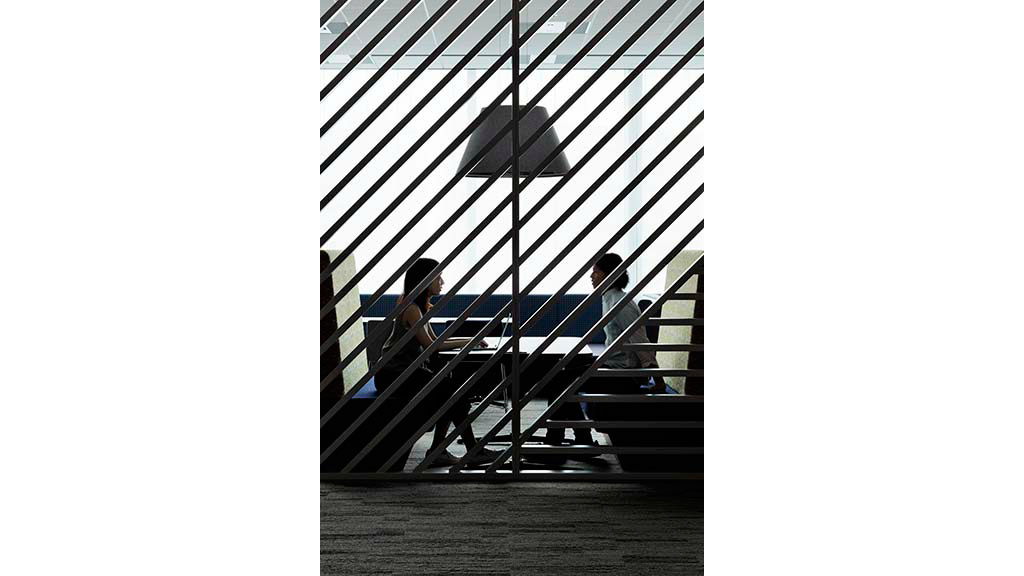 A couple of people sitting on a bench in front of a large window.