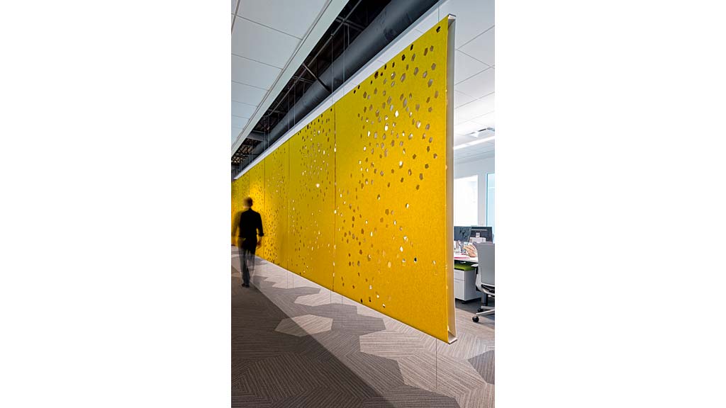 A person walking next to a large yellow wall.