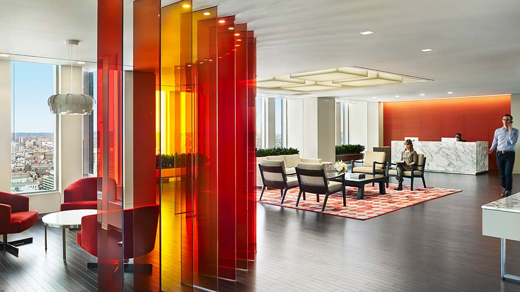 A room with red walls and a couple of people sitting at tables.
