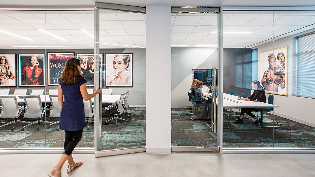 A person taking a picture of a glass wall with a glass door.
