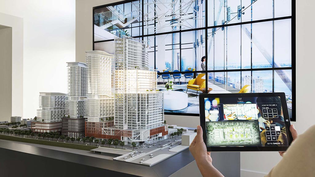 A person holding a tablet in front of a window with a city skyline.