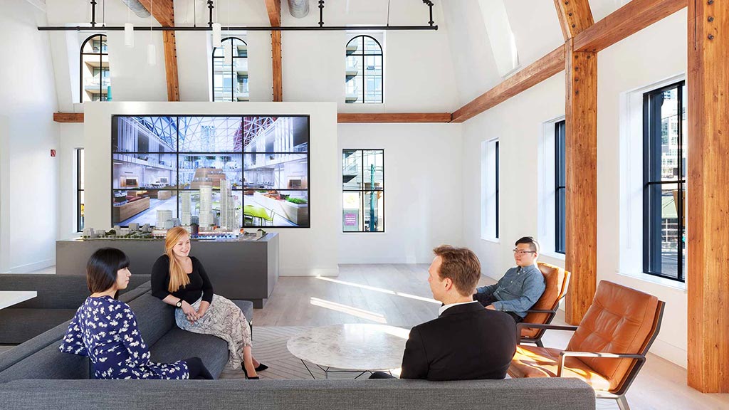 A group of people sitting in a room with a large screen.