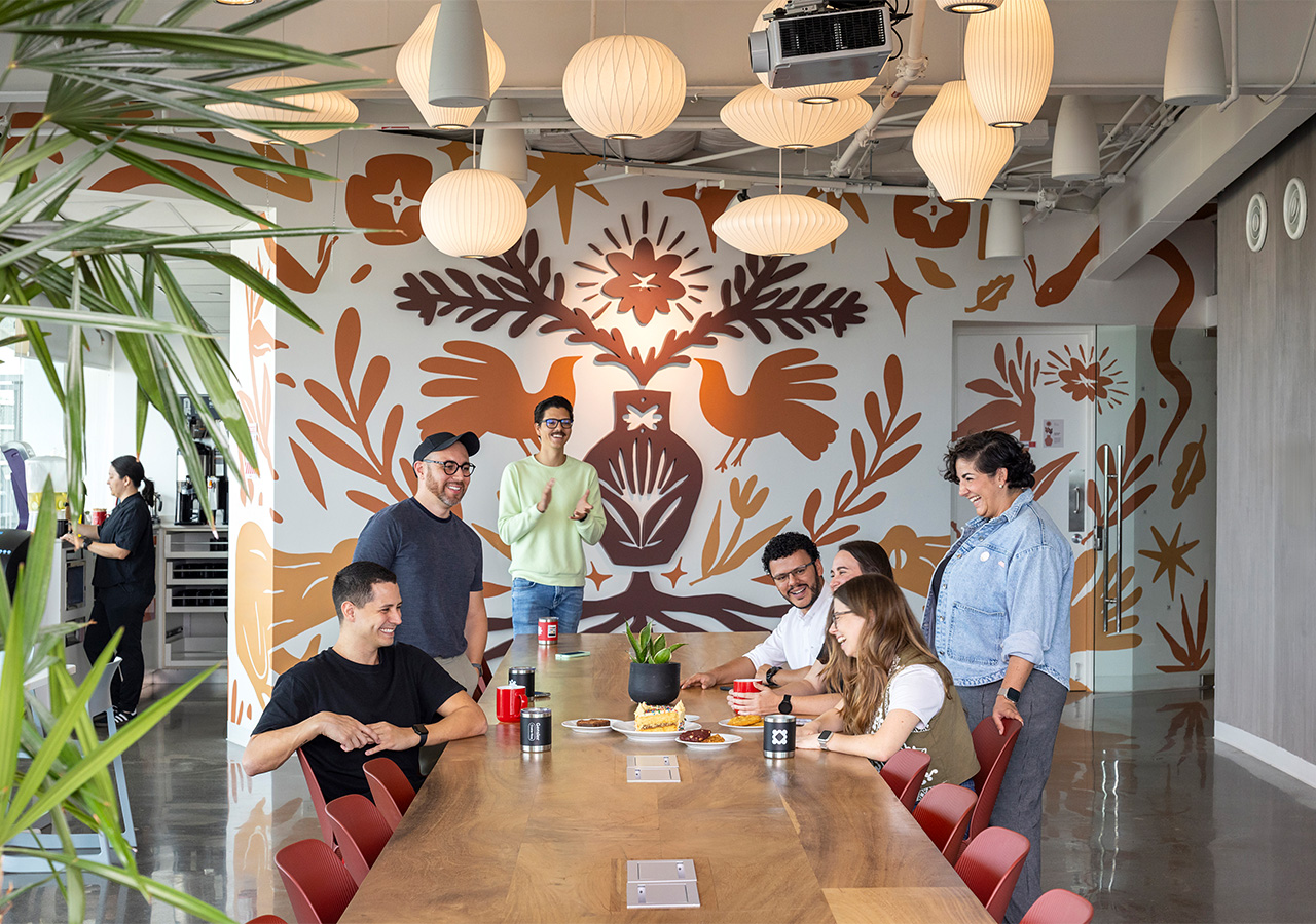 A group of people sitting around a table with food and drinks.