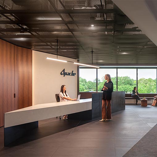 A person standing next to a person sitting on a bench.