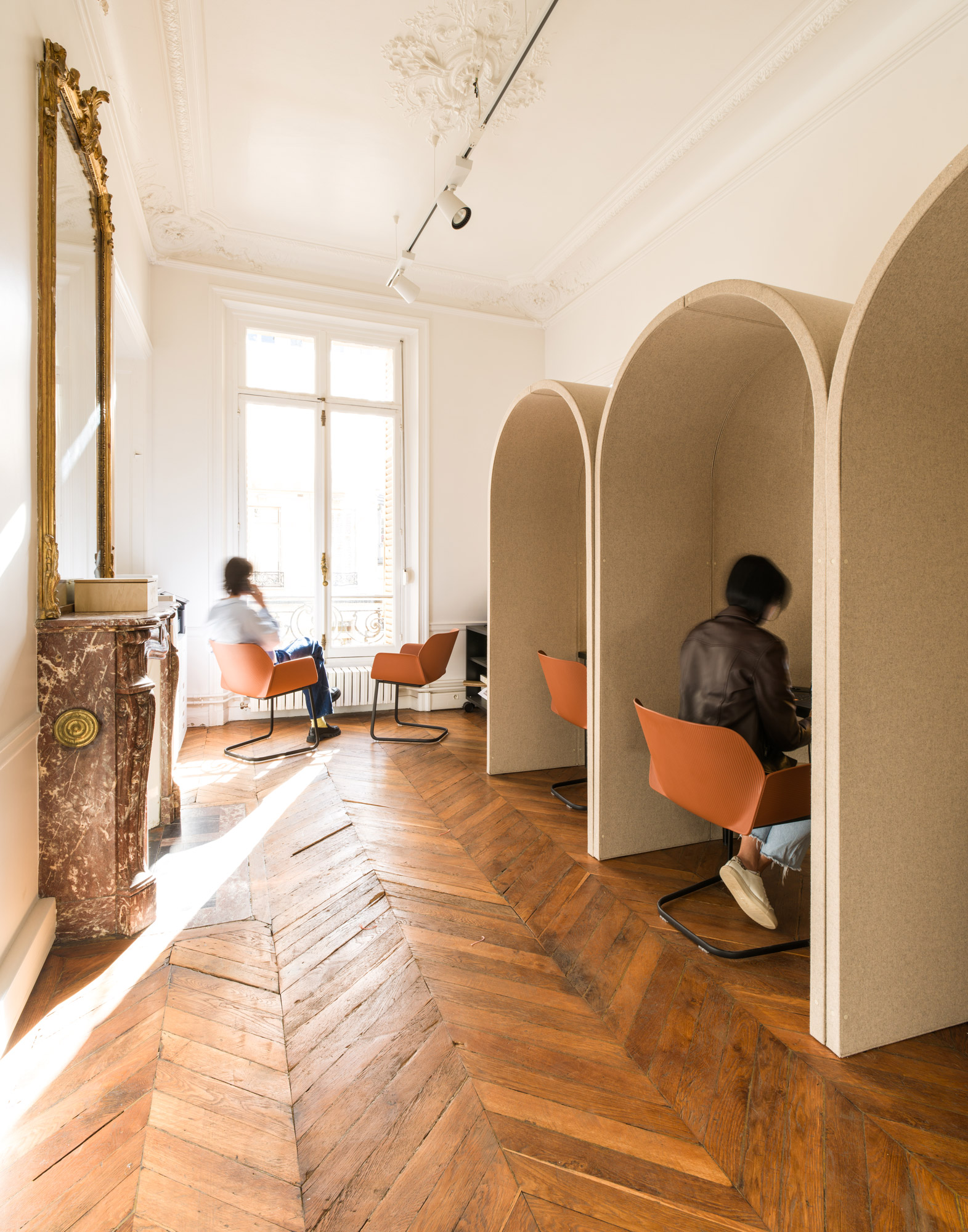 A man and a woman sitting in a room with a wood floor.