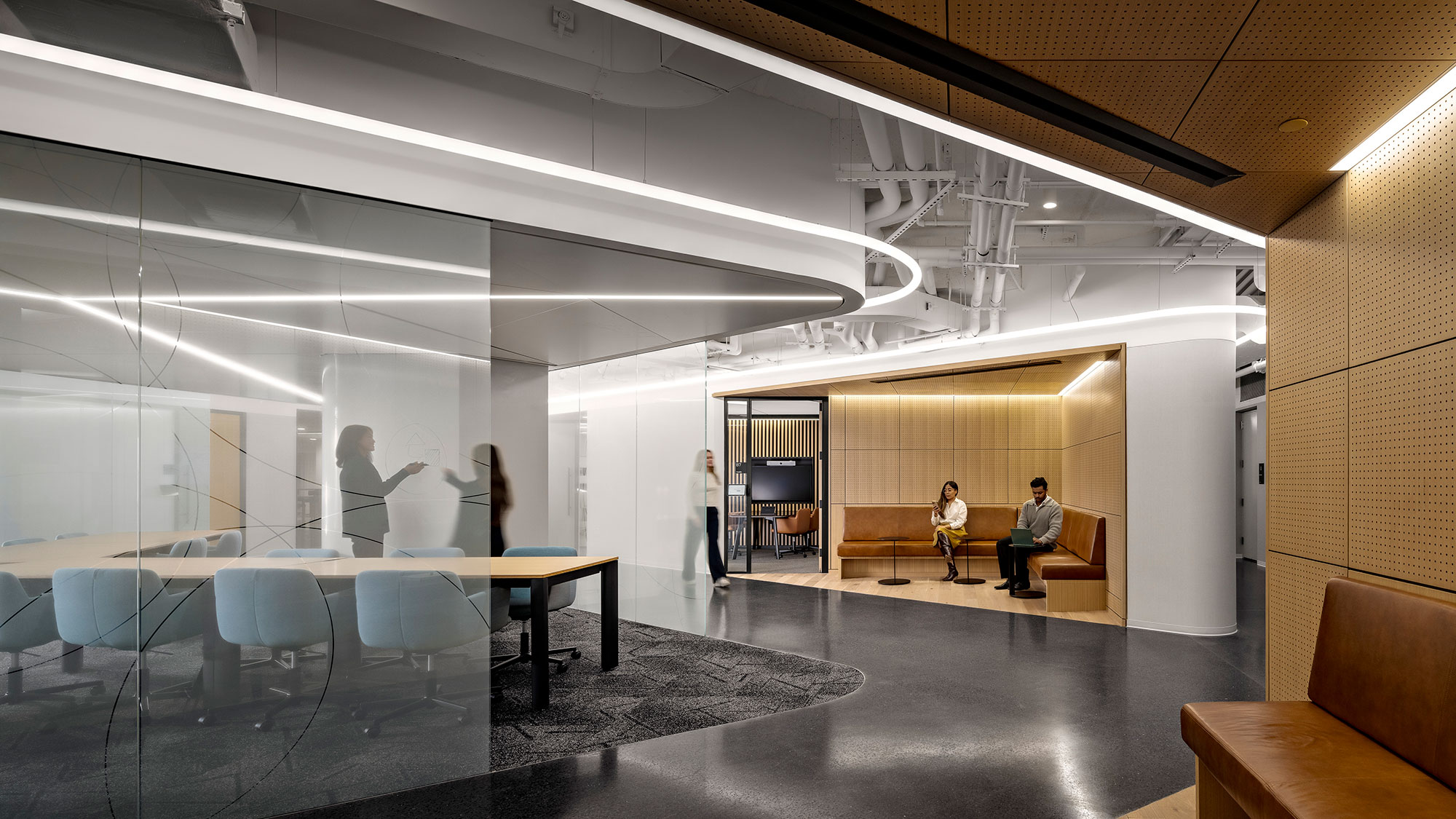A room with a large glass wall and a couple people sitting at a table.