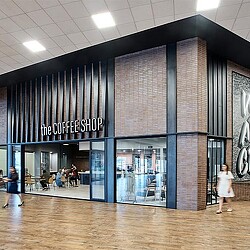 A person walking in front of a building with glass windows.