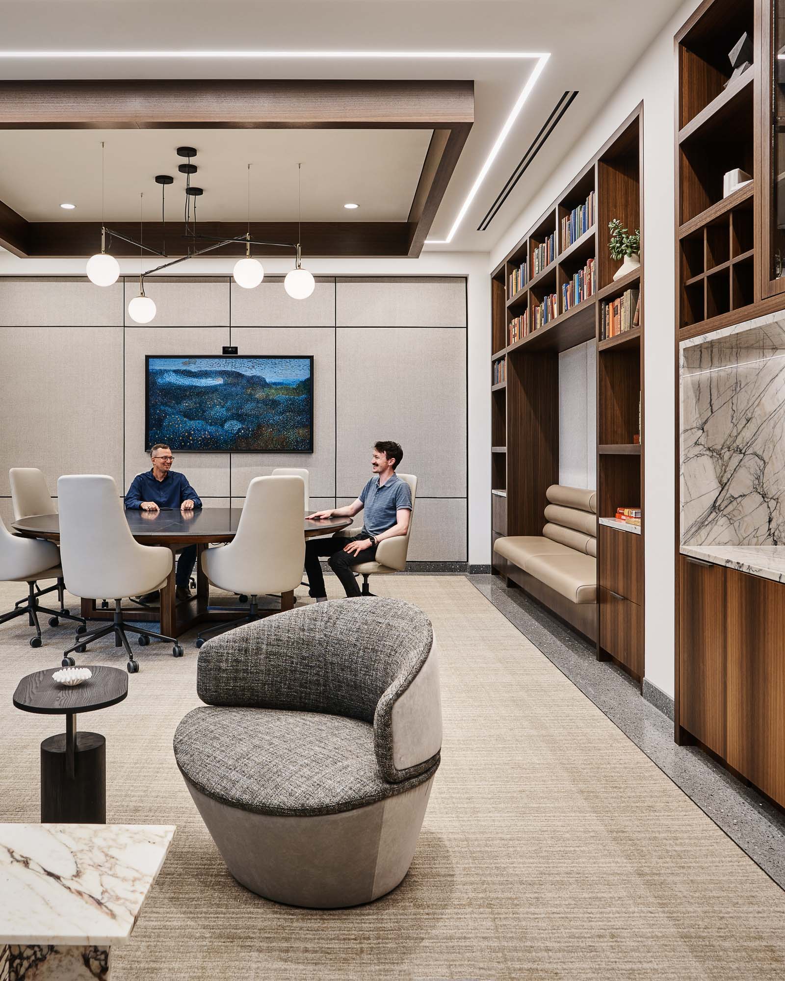 A couple of men sitting at a table in a library.