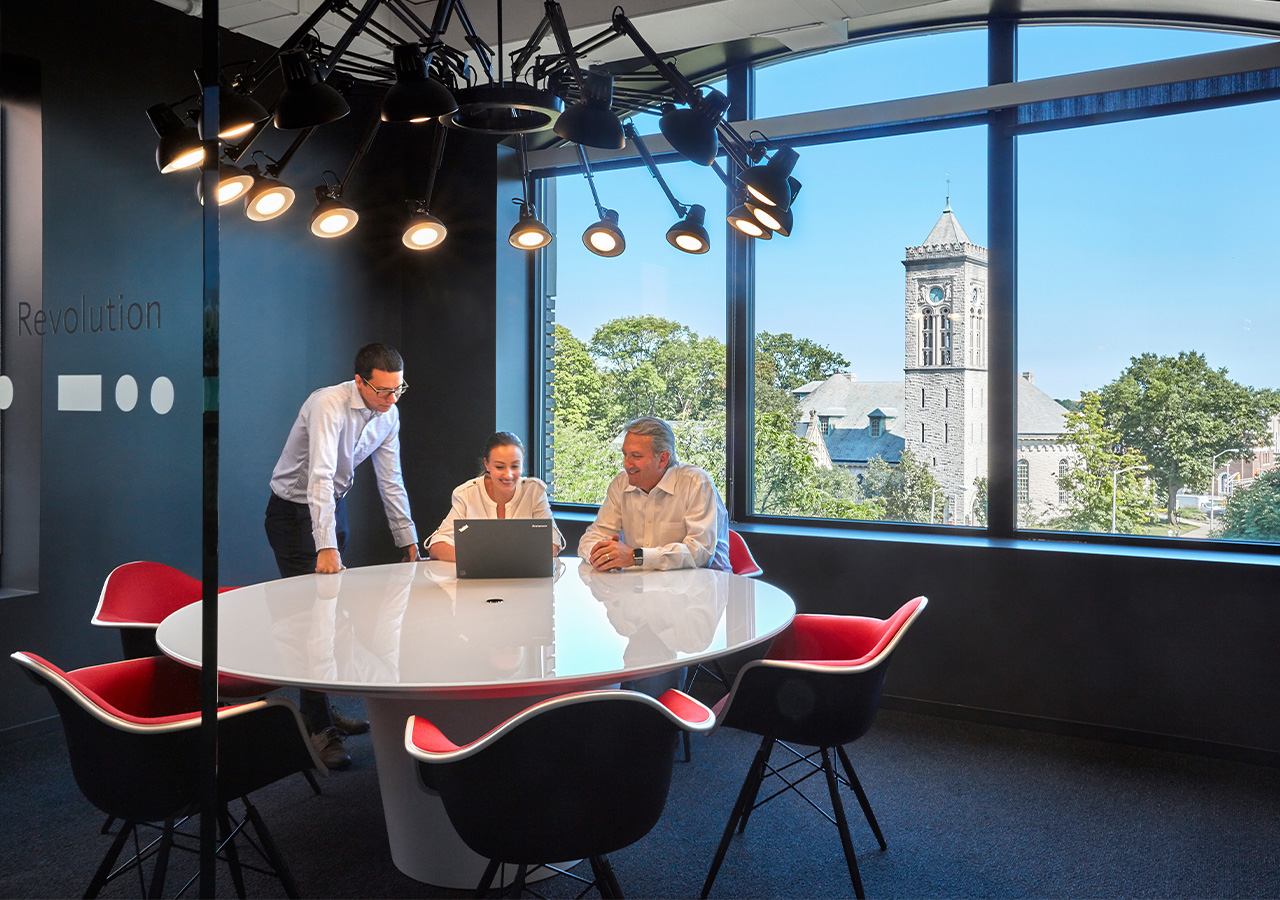 A group of people sitting at a table in a room with a large window.