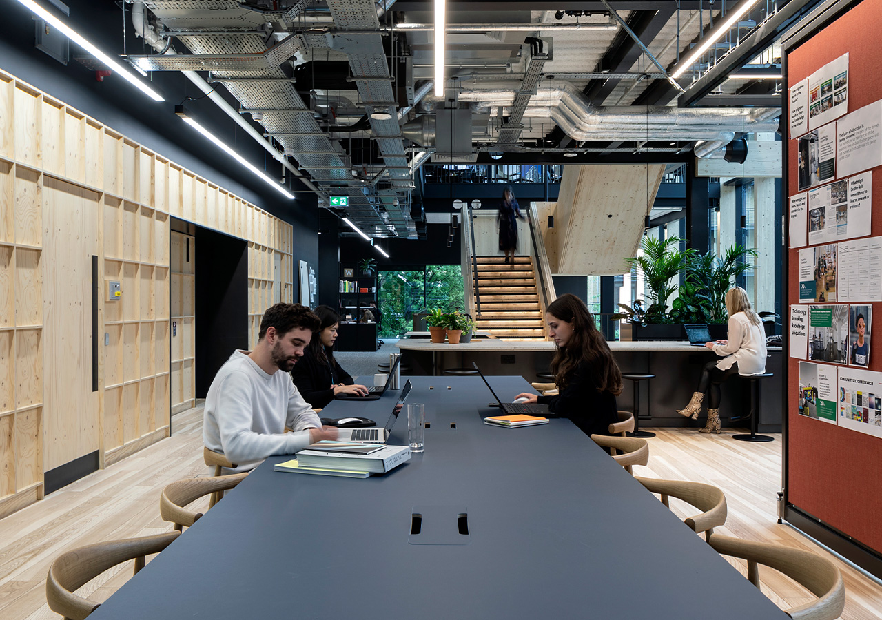 A group of people sitting at a table with laptops.