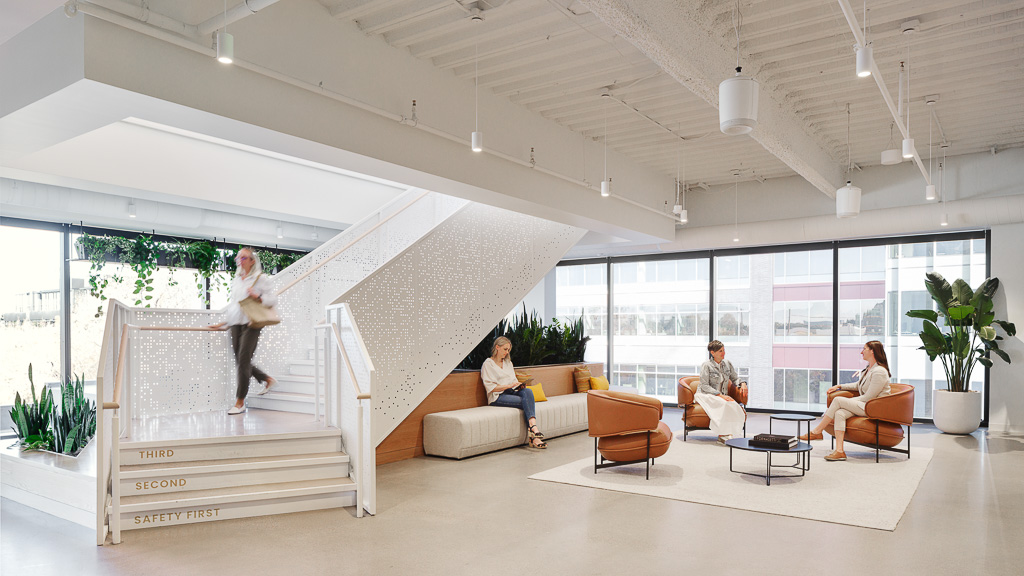 A group of people sitting in a room with a staircase.
