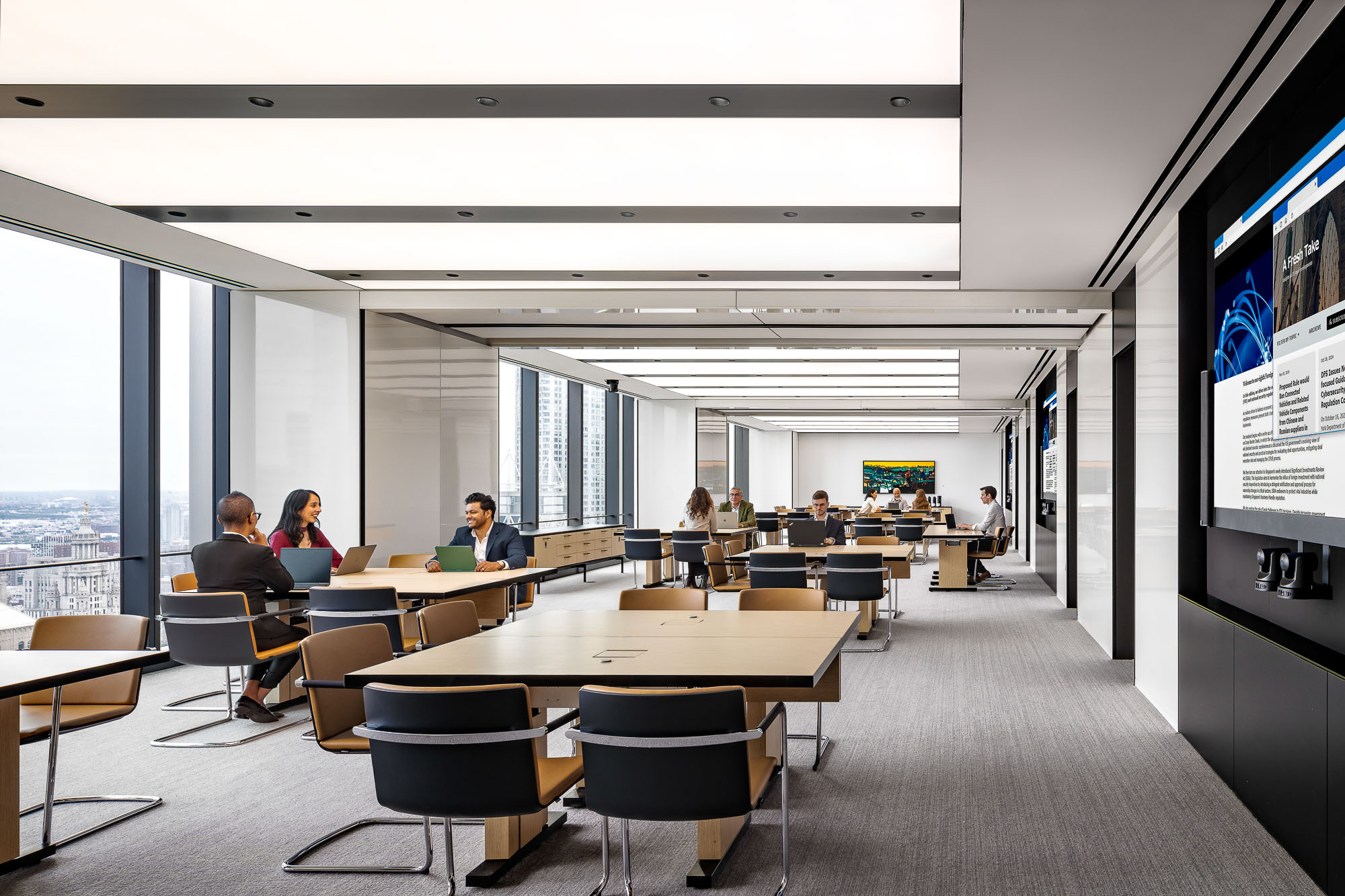 A group of people sitting at tables in a room with large windows.