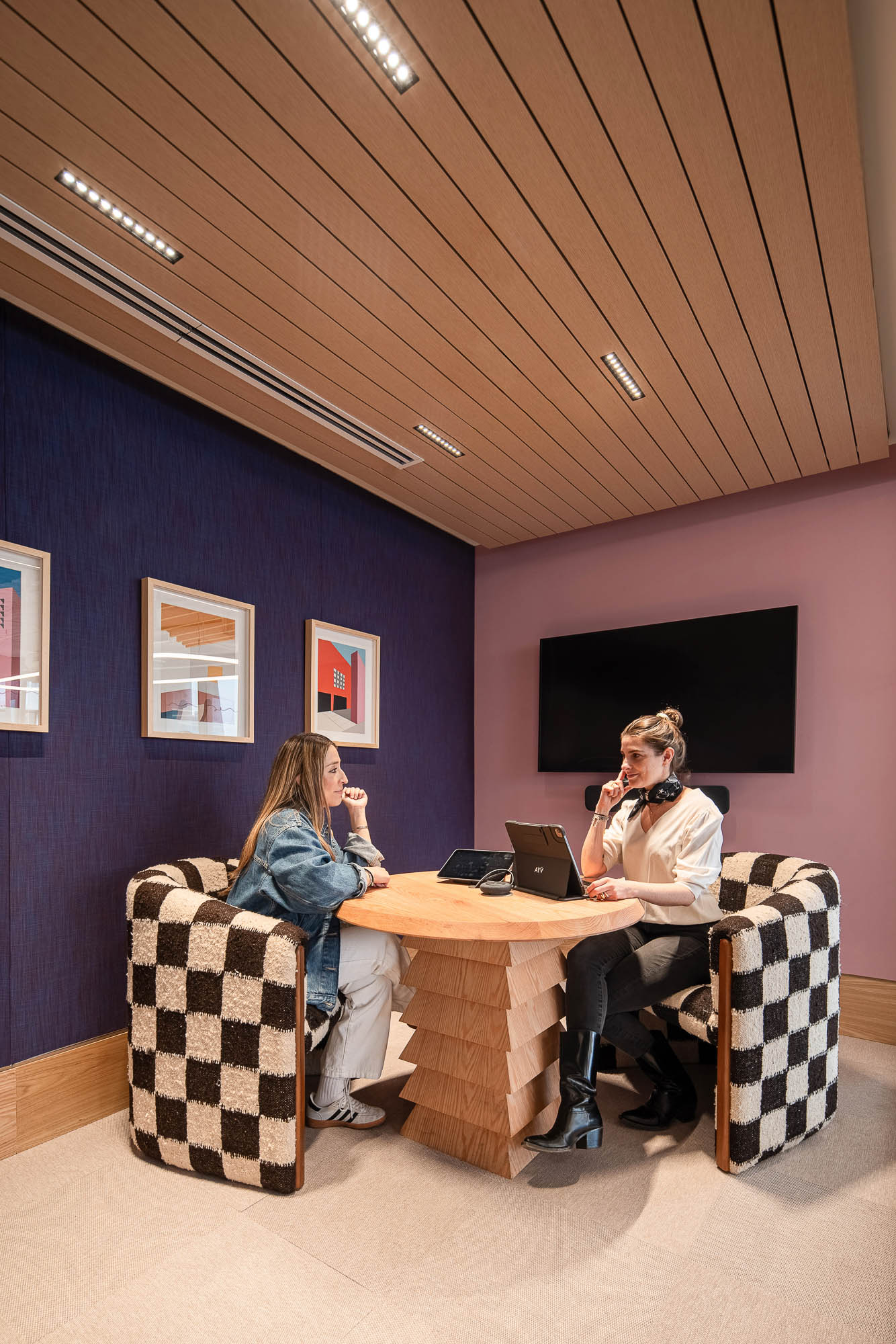 A couple of women sitting at a table with a laptop.