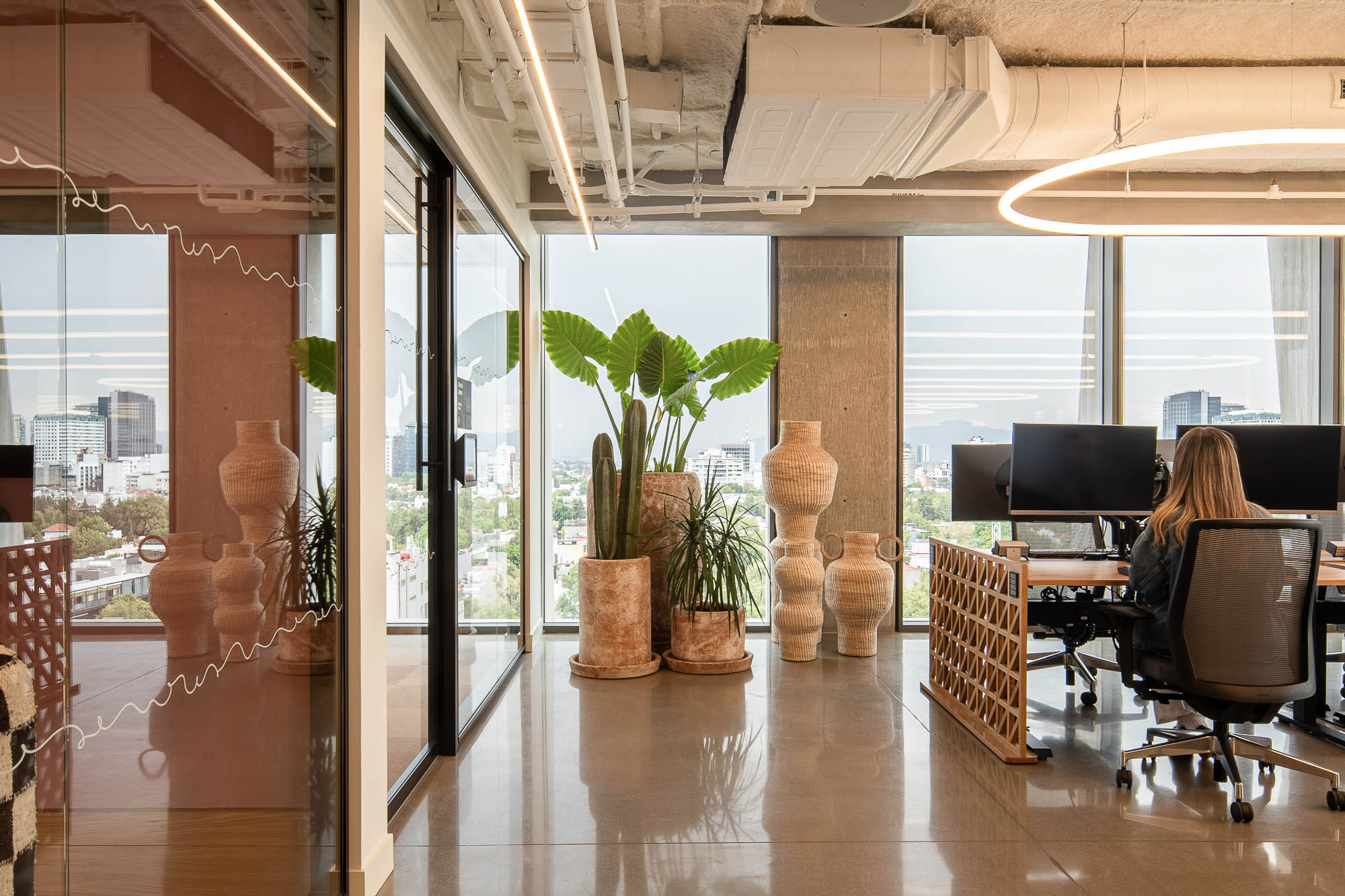 A person sitting at a desk in a room with large windows.