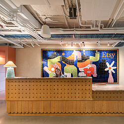 A person sitting on a bench in a room with a large painting.