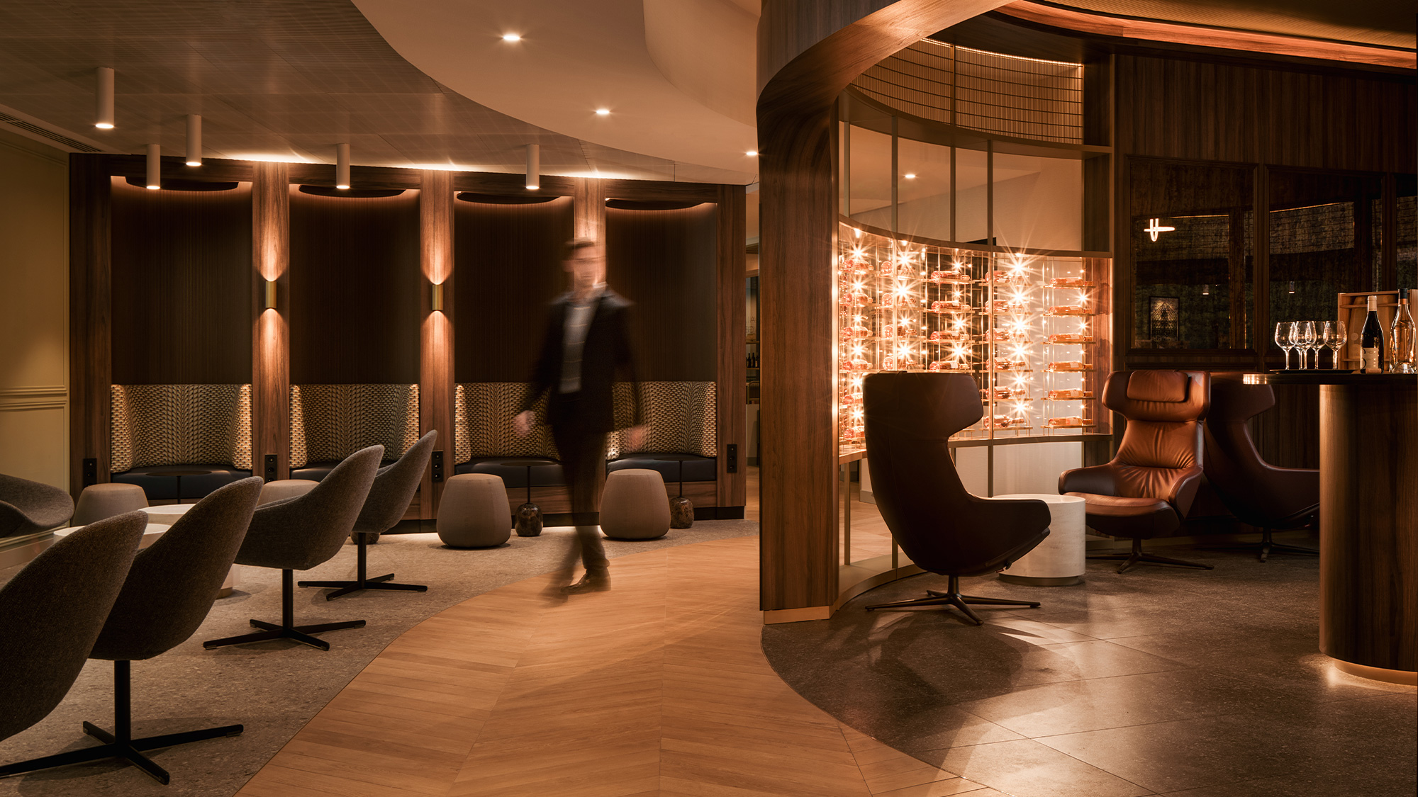 A person walking in a room with chairs and a large window.