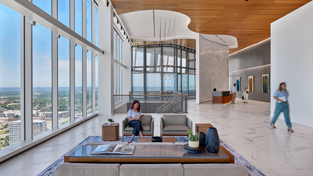 A person sitting on a chair in a room with large windows.