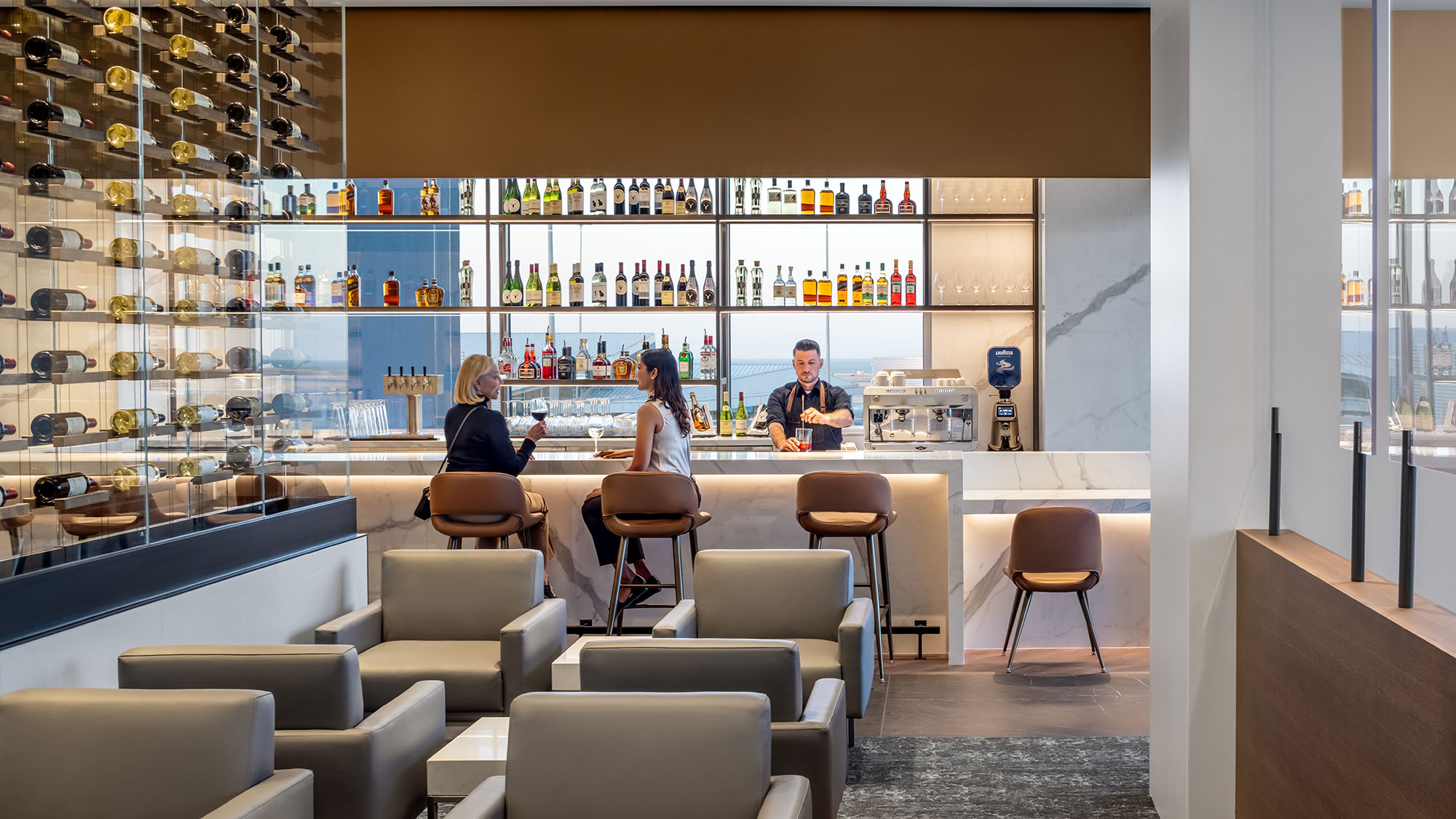 A group of people sitting at a table in a room with shelves of wine.