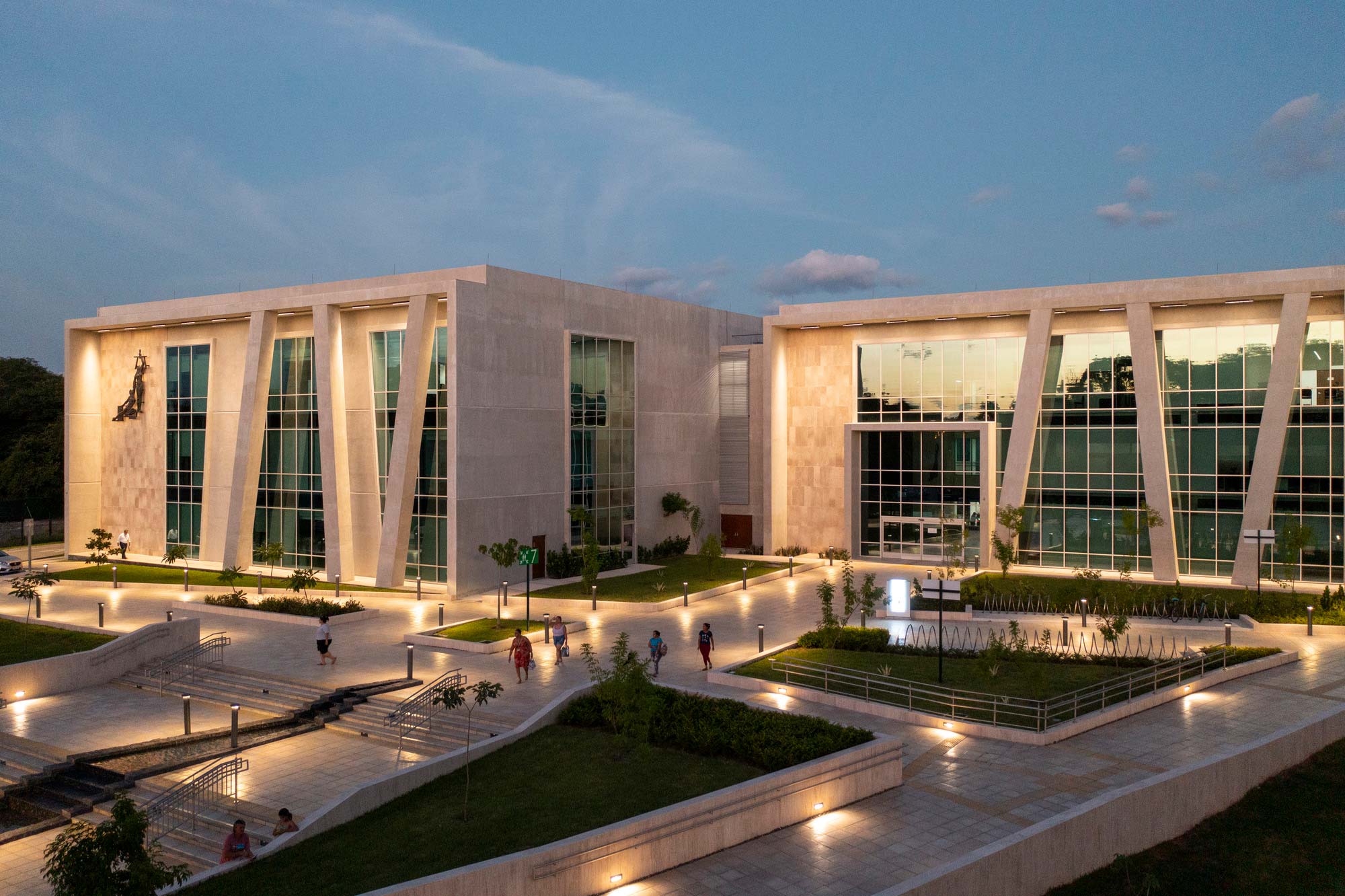 A large building with a courtyard and people walking around.