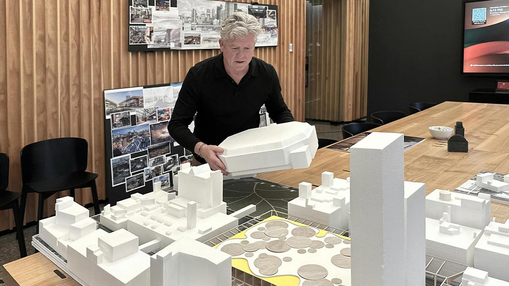 A person standing next to a table with a model of a building.