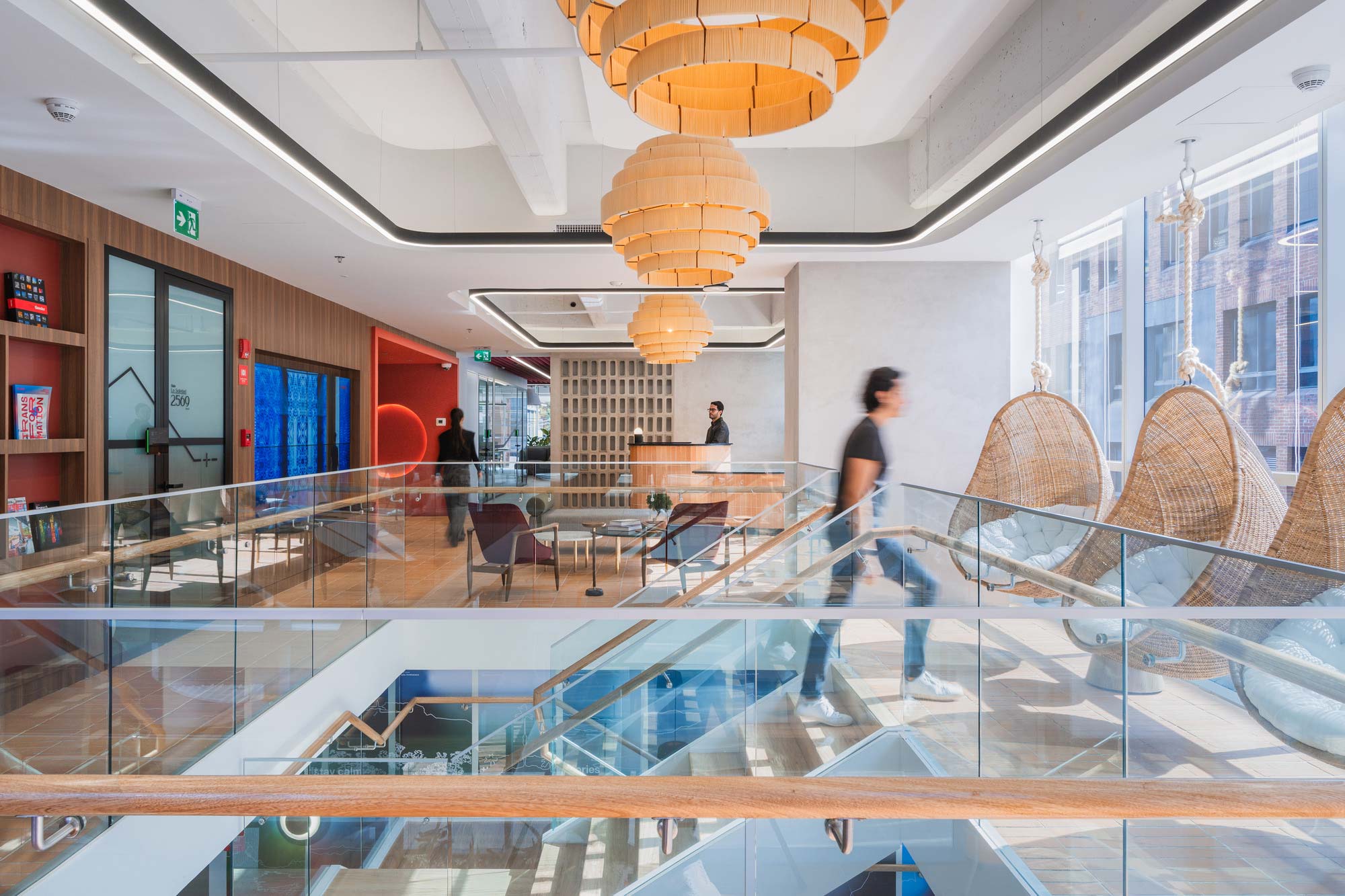 A glass walled building with people walking around.