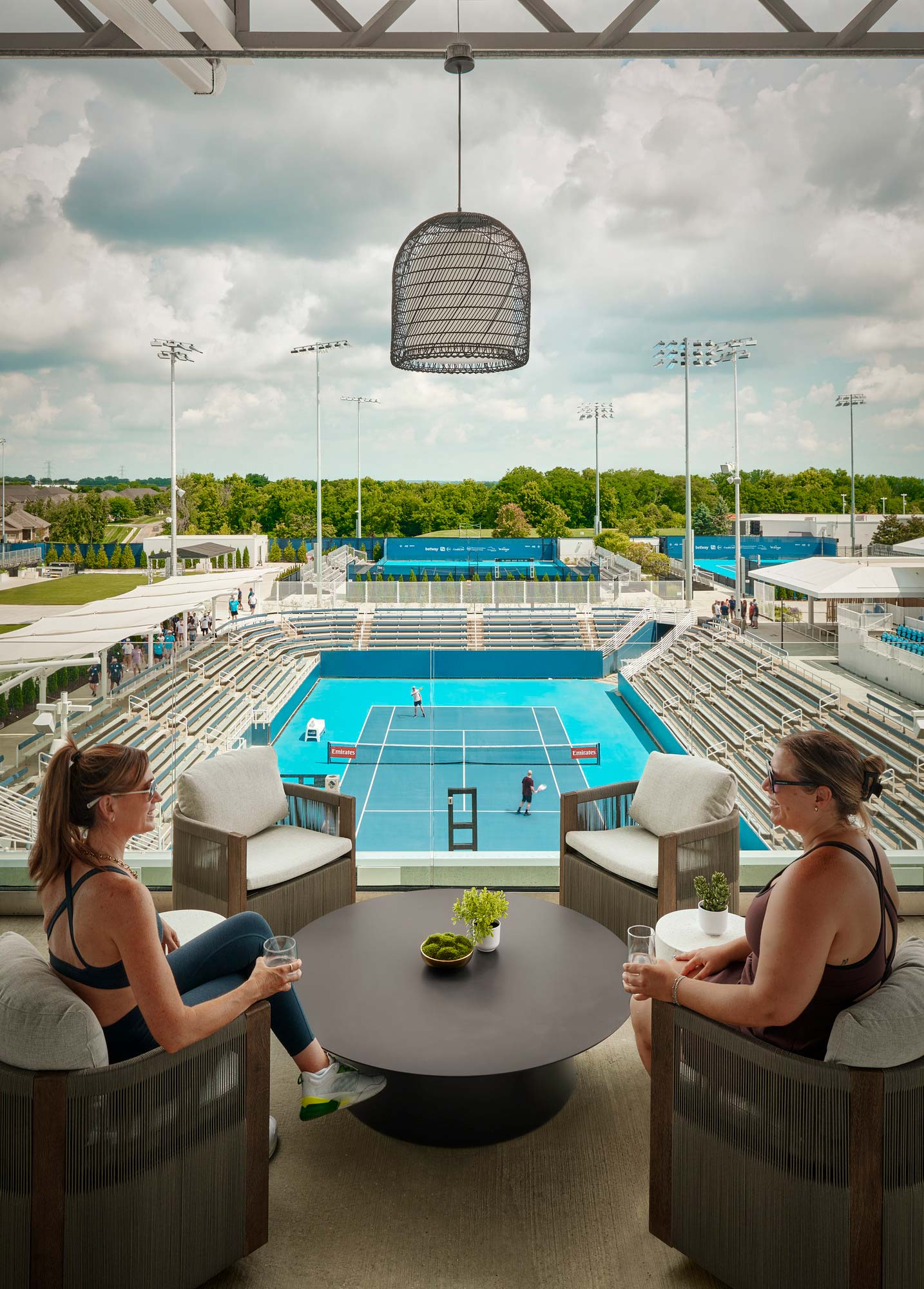 A couple of women sitting at a table by a pool.