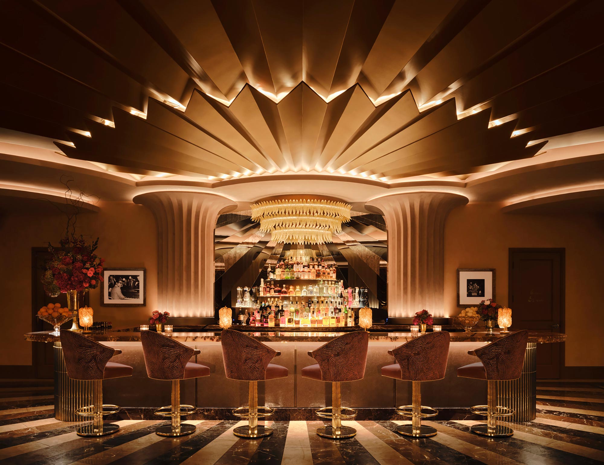 A fancy dining room with chandelier and chairs.