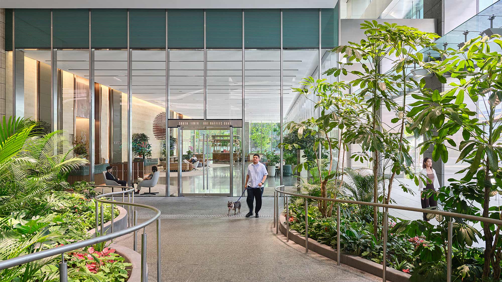 A man and a woman walking a dog in a building.