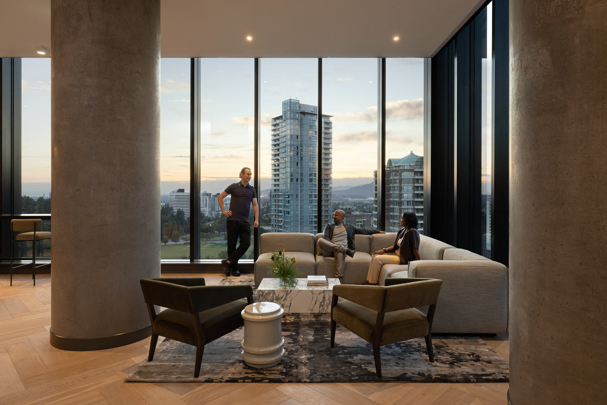 A group of people sitting on a couch in a room with large windows.